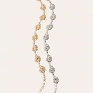Detailed view of gold and silver conch shell waist chains with textured metal spirals