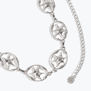 Détail de la ceinture chaîne étoile argentée avec breloques étoiles et pendentif fleur