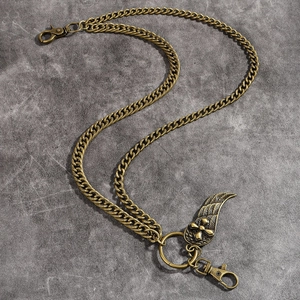 Close-up of vintage bronze pant chain with cross embossed wing pendant and ring detail