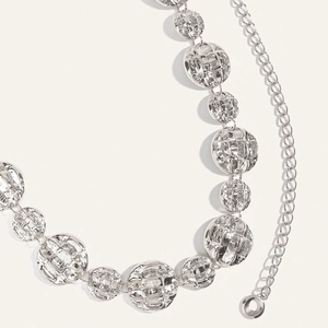 Close-up of silver metal waist chain featuring round hammered discs and adjustable link clasp