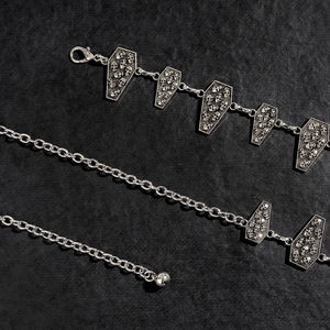 Macro view of gothic silver waist chain with coffin pendants and skull engravings