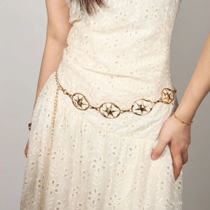 Détail d'une chaîne de taille dorée avec motif d'étoiles sur une robe en dentelle