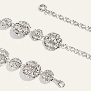 Macro view of silver metal waist chain showing crocodile-textured round discs and clasp
