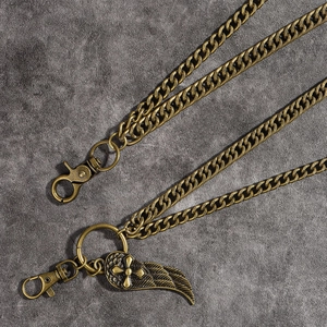 Detailed macro view of vintage bronze pant chain with wing and cross pendant charm