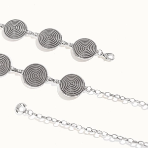 Vue détaillée d'une chaîne de taille ethnique argentée avec des disques à texture spirale
