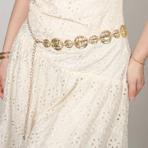 Detailed view of bohemian gold metal chain belt with embossed round discs on white dress
