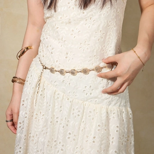 Detail of vintage gold metal waist chain with hollow flower patterns on white dress