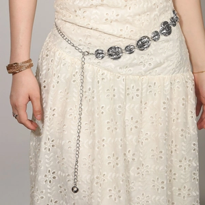 Detail of silver metal waist chain with embossed oval plates on white dress