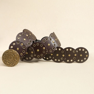 Detail eines Western-Vintage-Gürtels mit braunen Lederscheiben und goldener Blumenschnalle