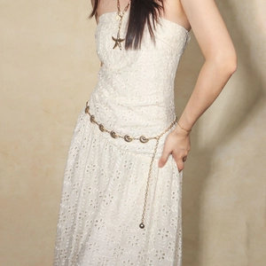 Detailed view of a golden shell metal waist chain with starfish charms on a lace dress
