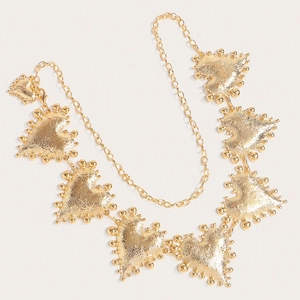 Detailed view of golden heart-shaped belt chain with vintage hammered texture