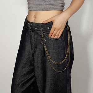 Detail view of retro bronze trouser chain with feather pendant on black jeans