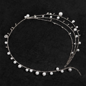Elegant multi-layer pearl waist chain with shell pendant on a black textured background