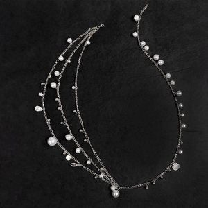 Detail of layered silver body chain featuring white pearls and shell star pendants