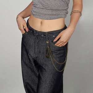 Close-up of vintage bronze metal chain and safety pin decoration on dark denim jeans