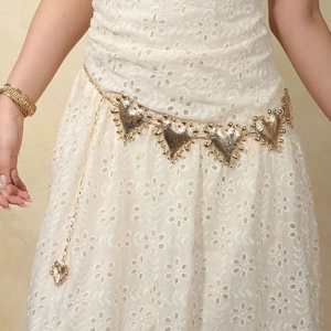 Detail of vintage gold heart-shaped metal belt and textured multi-layer bracelets