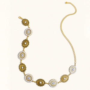 Detail of bohemian gold metal waist chain with embossed discs and faux marble floral inlays