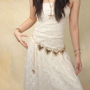 Detail of a vintage golden heart-shaped metal waist chain on a white dress