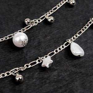 Macro detail of Bohemian silver waist chain with pearls and star pendants for Y2K style