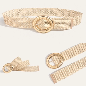 Detail of bohemian straw woven belt featuring a large gold oval buckle and leather end