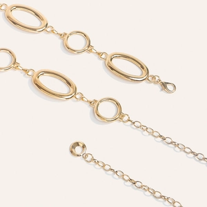 Detailed view of polished gold oval metal waist chain with adjustable lobster clasp