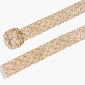 Detailed macro view of bohemian woven straw belt with an ornate golden metal buckle