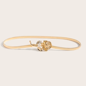 Détail de la ceinture dorée élastique avec une boucle en forme de rose métallique en relief