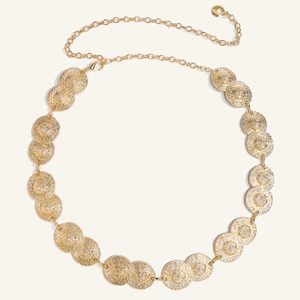 Macro shot of gold metal chain belt featuring spiral sun pattern textured circular discs