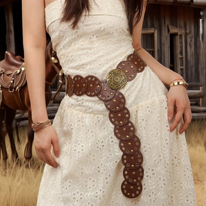 Detail eines Bohème-Ledergürtels mit Vintage-Metallschnalle auf einem Spitzenkleid