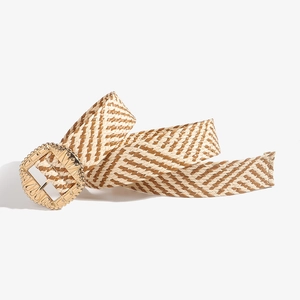 Close-up of bohemian woven belt with brown straw patterns and engraved gold buckle