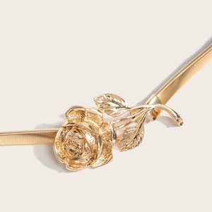 Détail d'une boucle rose dorée et d'une chaîne en métal élastique pour robe de femme