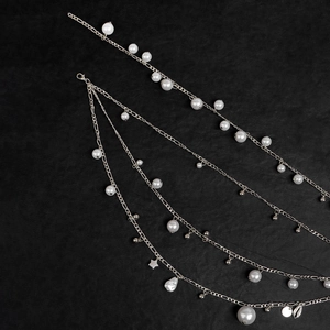 Double-layered silver pearl waist chain with star and shell charms on black background