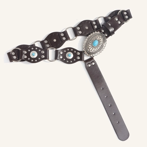 Detail view of western leather belt with turquoise studs and engraved metal buckle