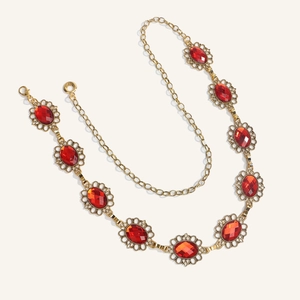 Dettaglio catena in metallo dorato vintage con gemme rosse e chiusura a moschettone