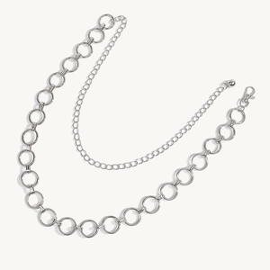 Detail van een dubbellaagse zilveren metalen tailleketing met grote holle ringen