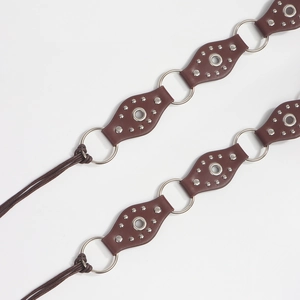 Detail of vintage studded leather belt with silver metal rings and braided ties