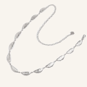 Macro detail of silver leaf charms and rose pendant on a metal chain belt