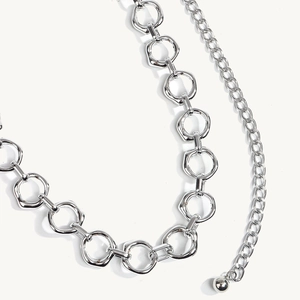 Close-up van vintage zilveren metalen tailleketing met geometrische ringen en bolhanger