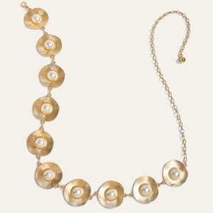 Detail of vintage gold metal waist chain featuring round sunburst discs and white pearls