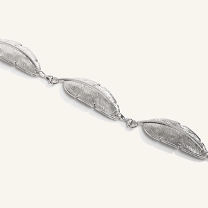 Detailed macro view of bohemian silver feather link chain with intricate textured engraving