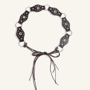 Detail view of retro punk leather waist belt with silver metal studs and tie closure