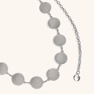 Detailed macro view of silver metal waist chain with textured circular pattern links