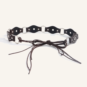 Detail view of dark brown leather diamond pieces and silver metal rings on a woven belt