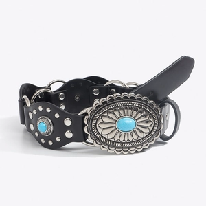 Dettaglio di cintura vintage boho con anelli argentati e fibbia solare con turchese