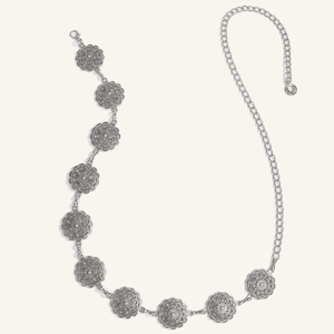 Dettaglio della cintura a catena in metallo argento vintage con motivi a medaglione