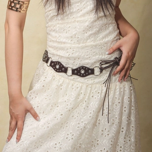Close-up of bohemian brown leather belt with metal rings, rivets and rhinestone details