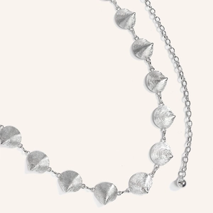 Detailed view of western retro silver metal waist chain with textured shell pendants