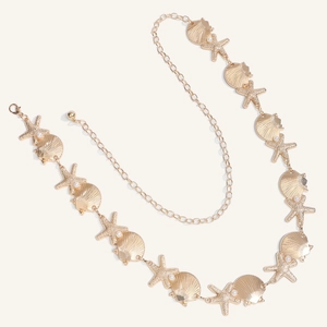 Macro detail of gold sea shell and starfish waist chain with faux pearls for summer