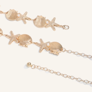 Close-up of golden sea star and shell waist chain with pearls and lobster clasp