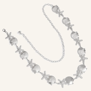 Detailed close-up of starfish and seashell charms on the silver metal waist chain